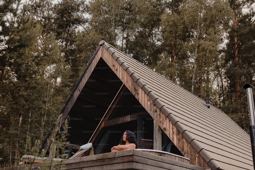 a woman is sitting on a balcony of a cabin