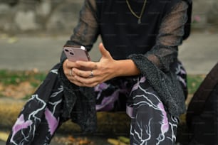a woman sitting on the ground holding a cell phone