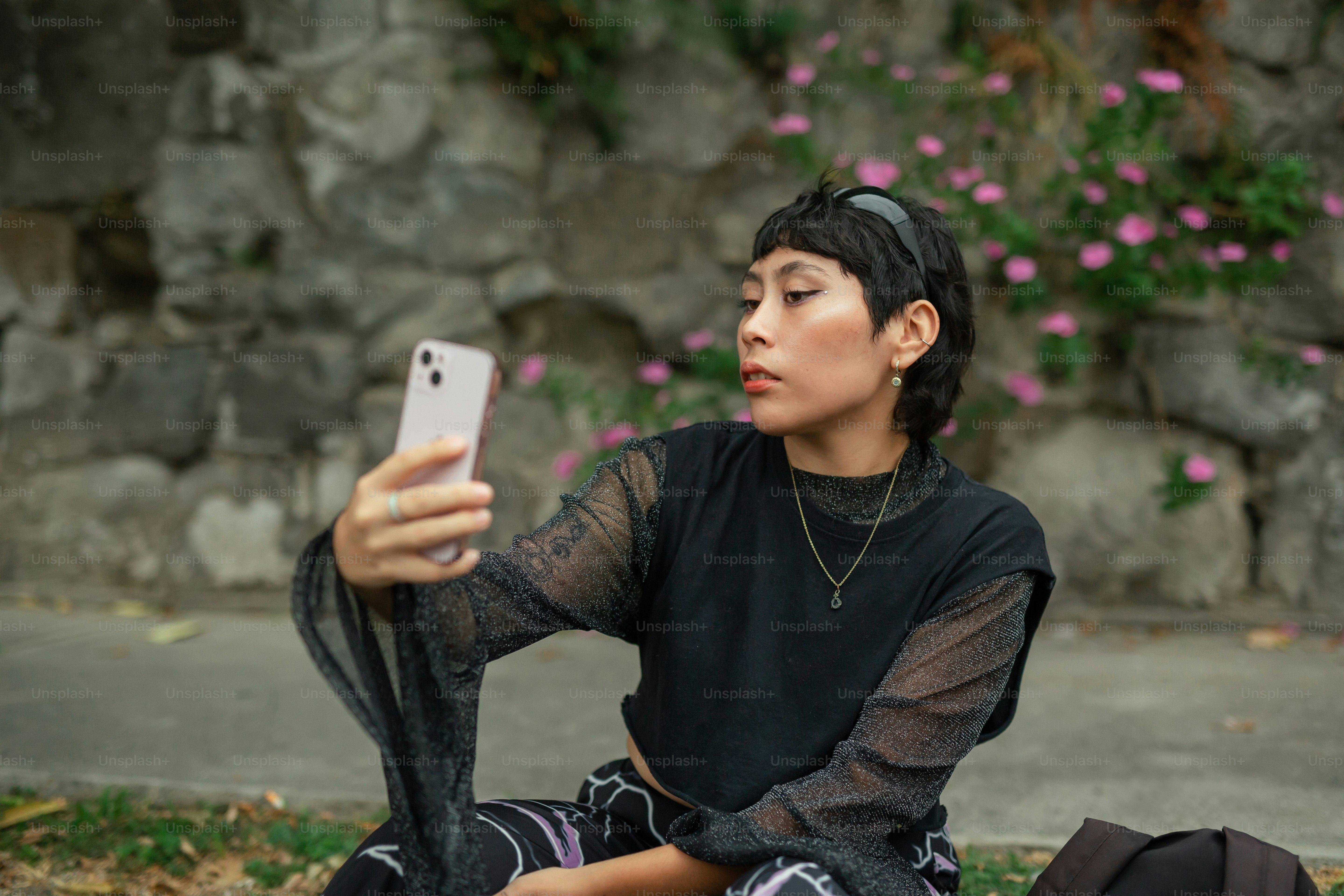 a woman sitting on the ground holding a cell phone