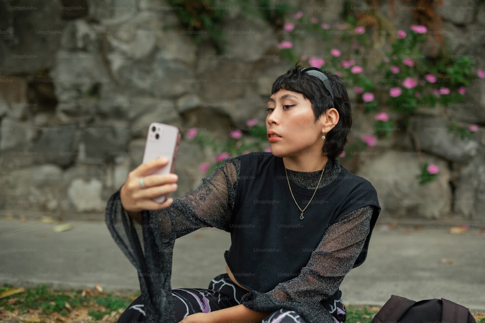 a woman sitting on the ground holding a cell phone