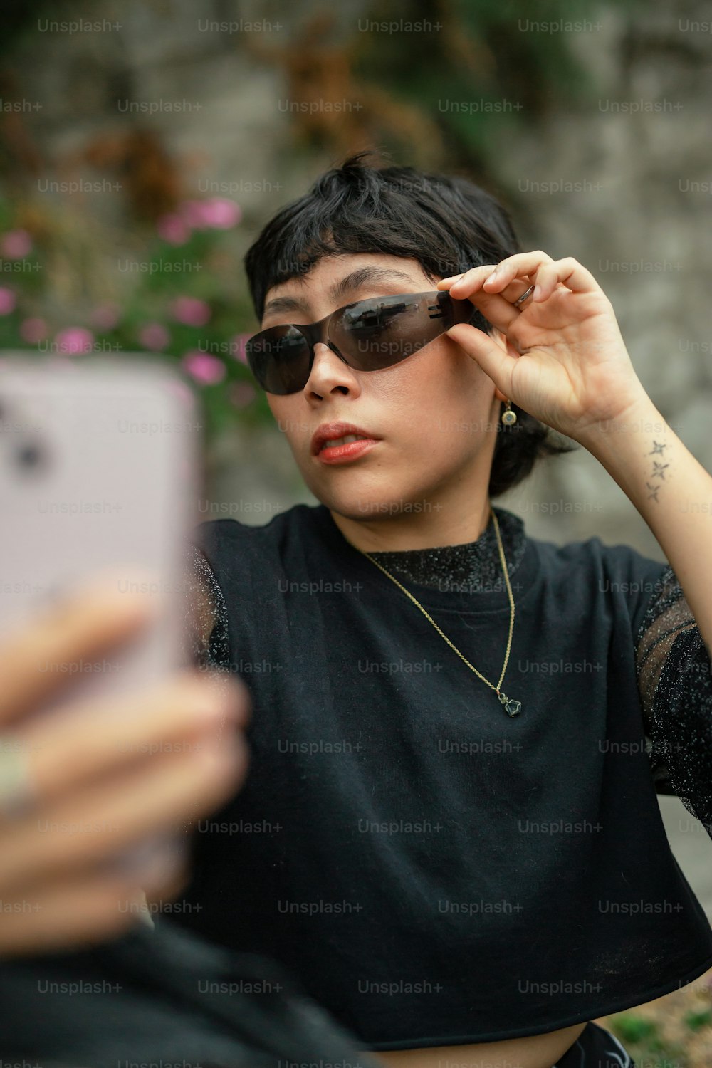 uma mulher usando óculos escuros olhando para um telefone celular