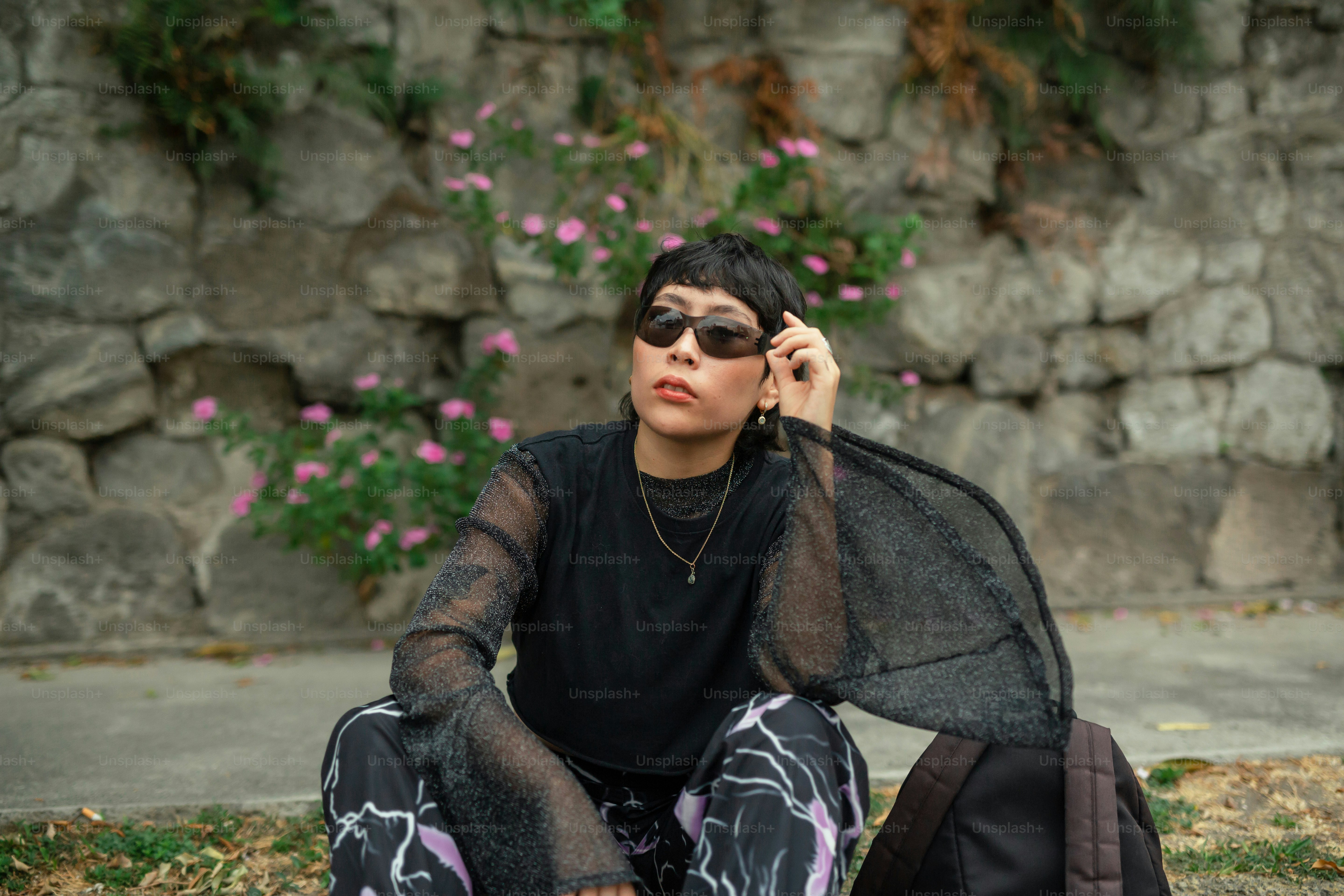 a woman sitting on the ground talking on a cell phone