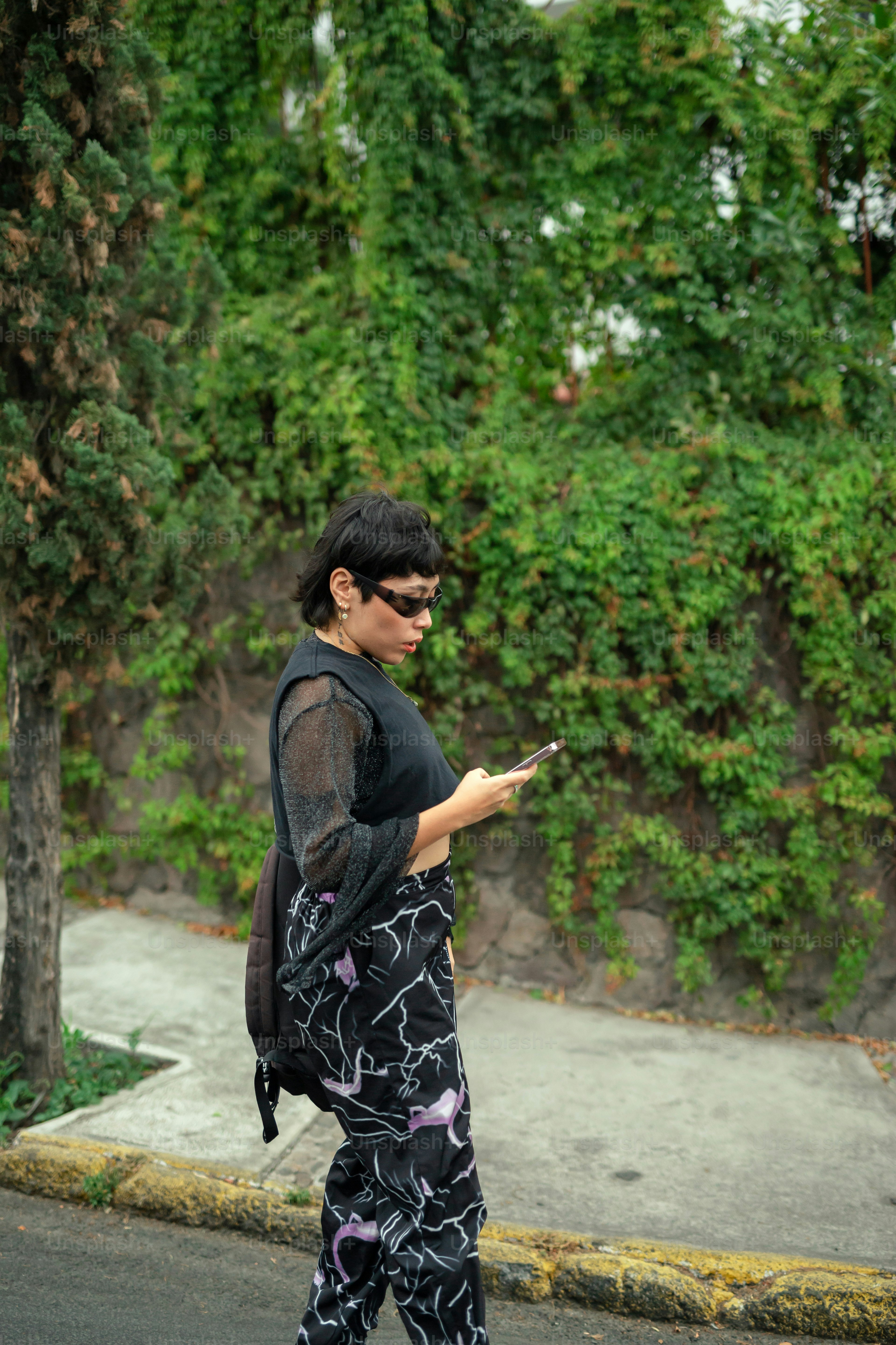 a woman walking down the street while looking at her cell phone