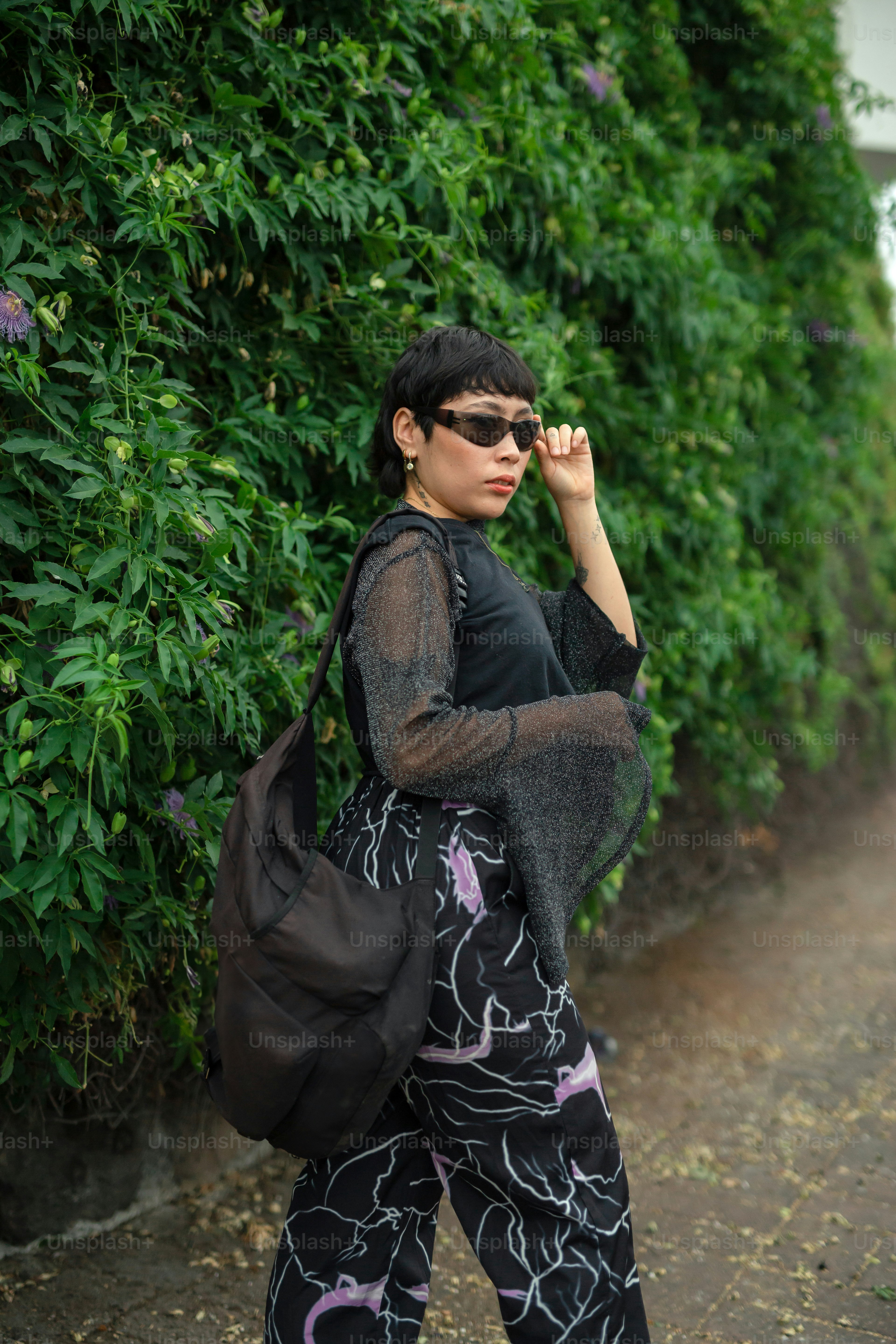A woman walking down a dirt road carrying a black bag photo Teen