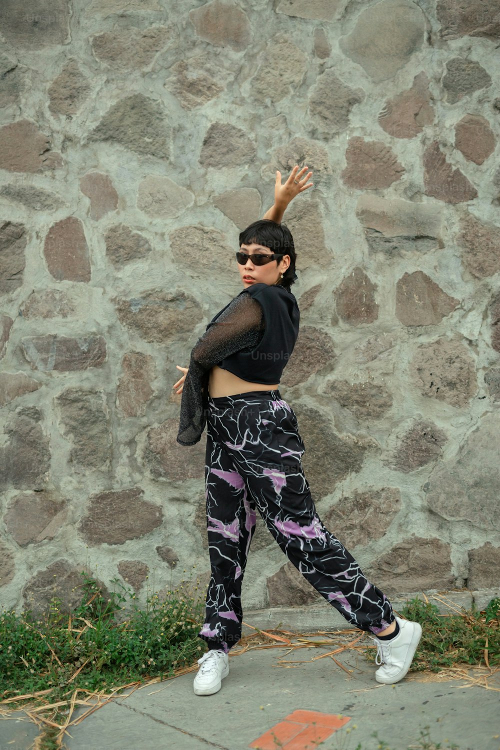 a woman in a black top and patterned pants