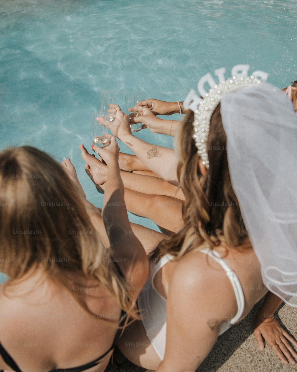 um grupo de mulheres sentadas uma ao lado da outra em frente a uma piscina