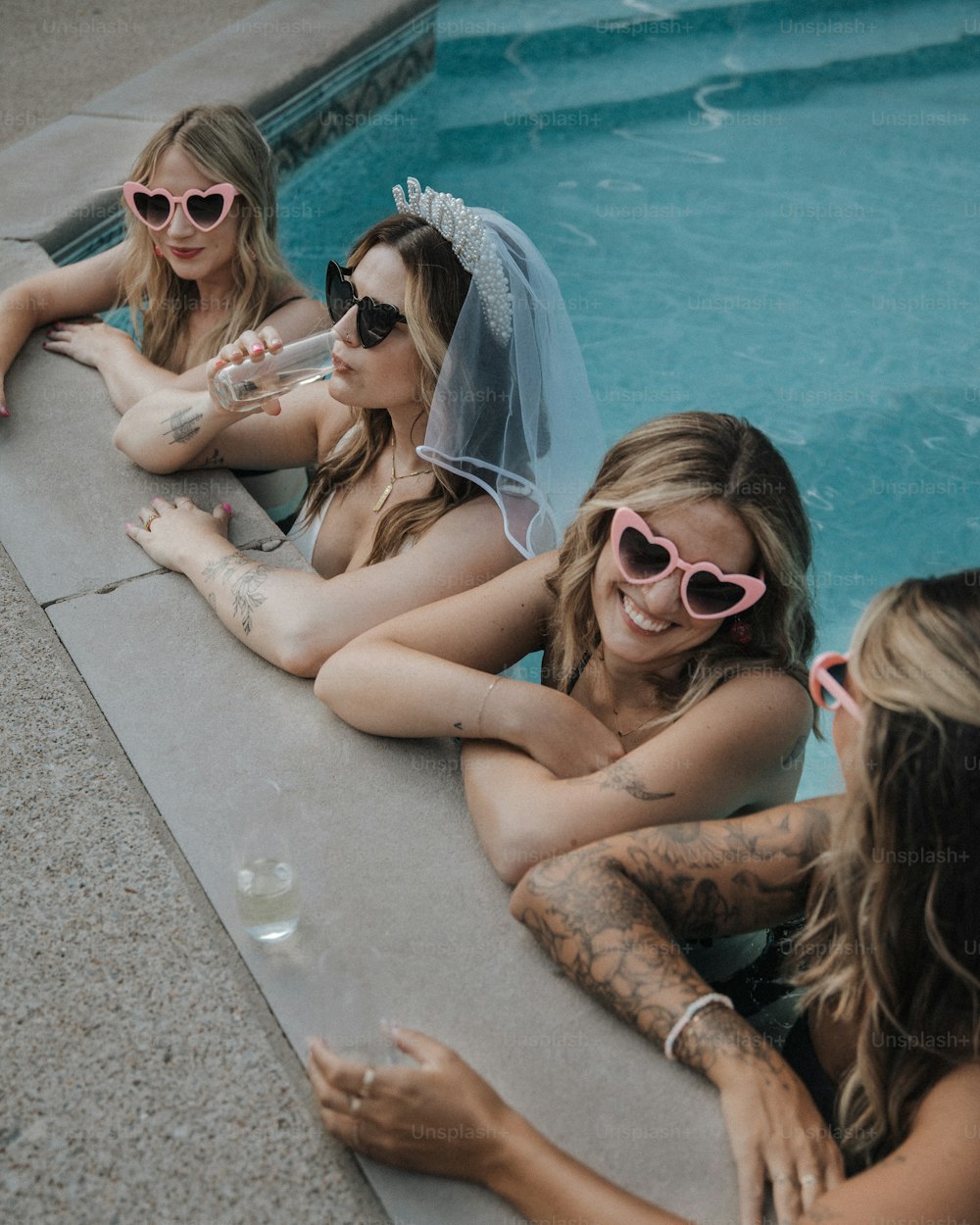 a group of women sitting next to a swimming pool