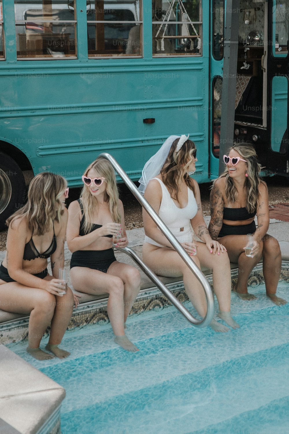 um grupo de mulheres sentadas uma ao lado da outra em frente a um ônibus azul