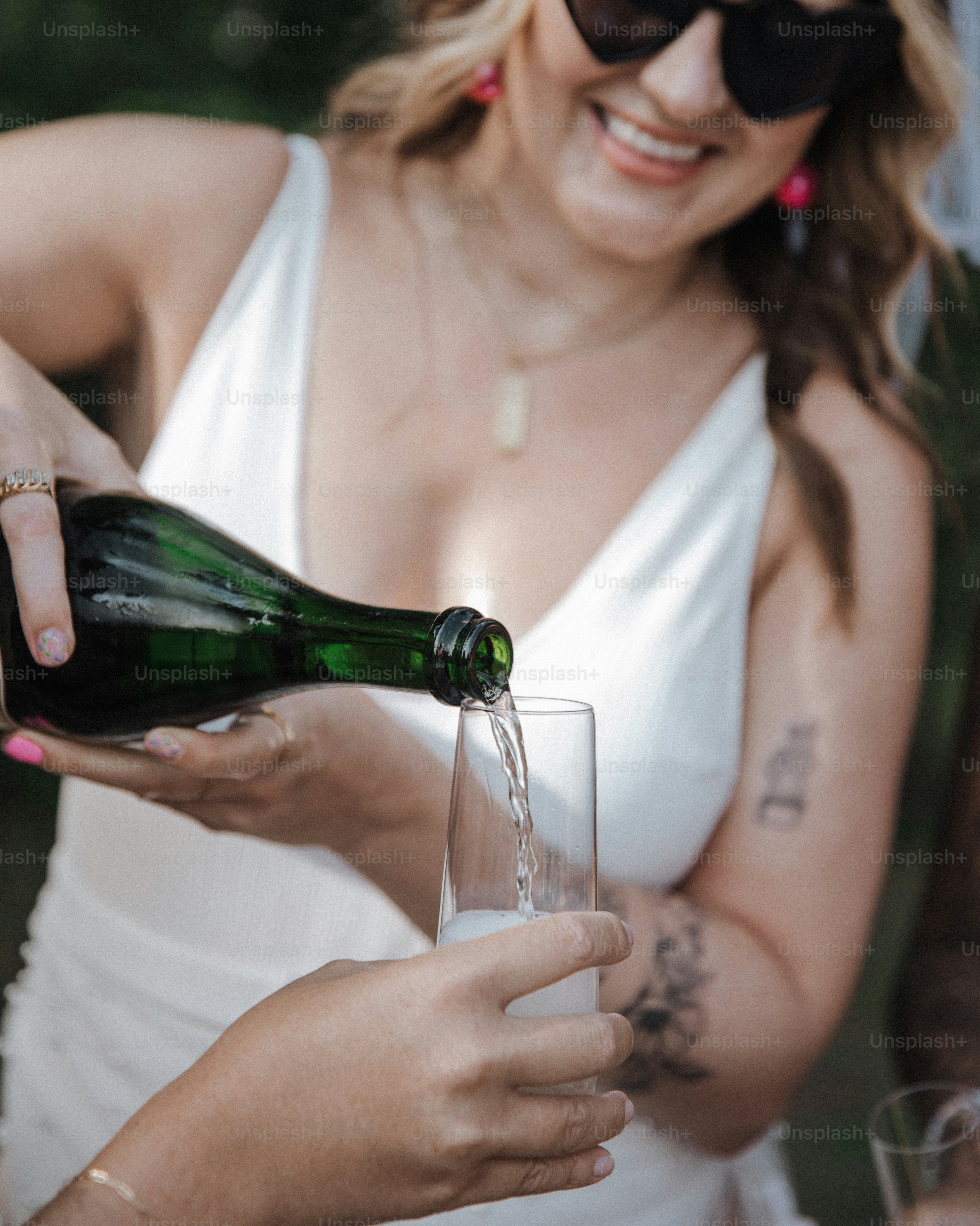 a woman in a white dress pouring a glass of wine