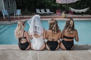 a group of women sitting next to a swimming pool