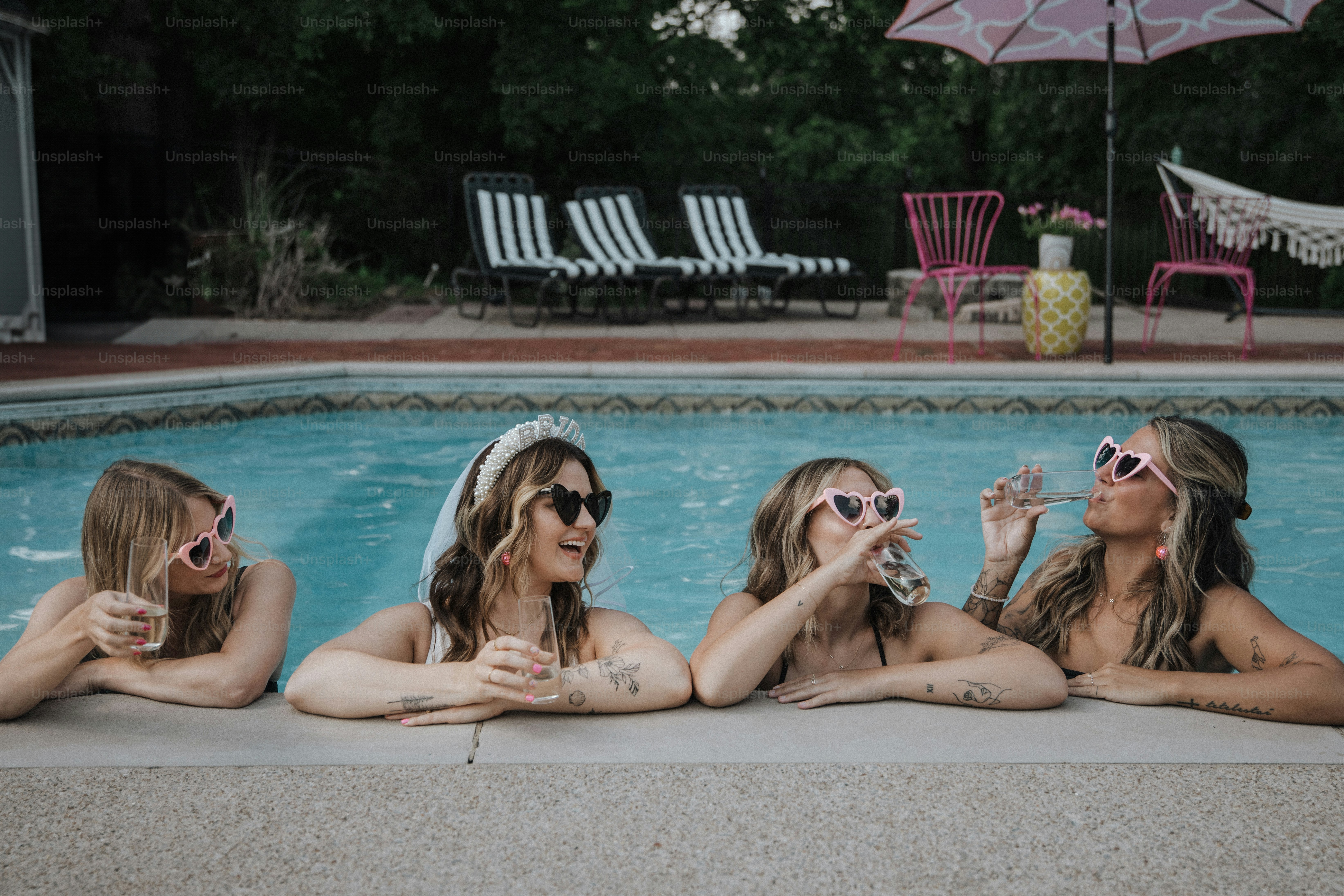 a group of women sitting next to a swimming pool