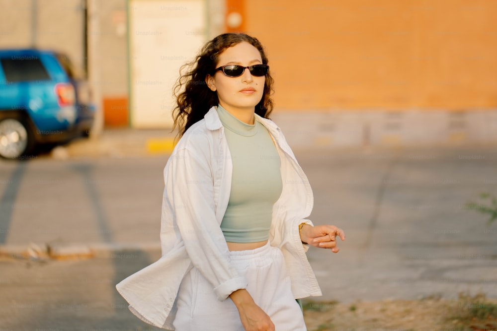 a woman walking down the street wearing sunglasses