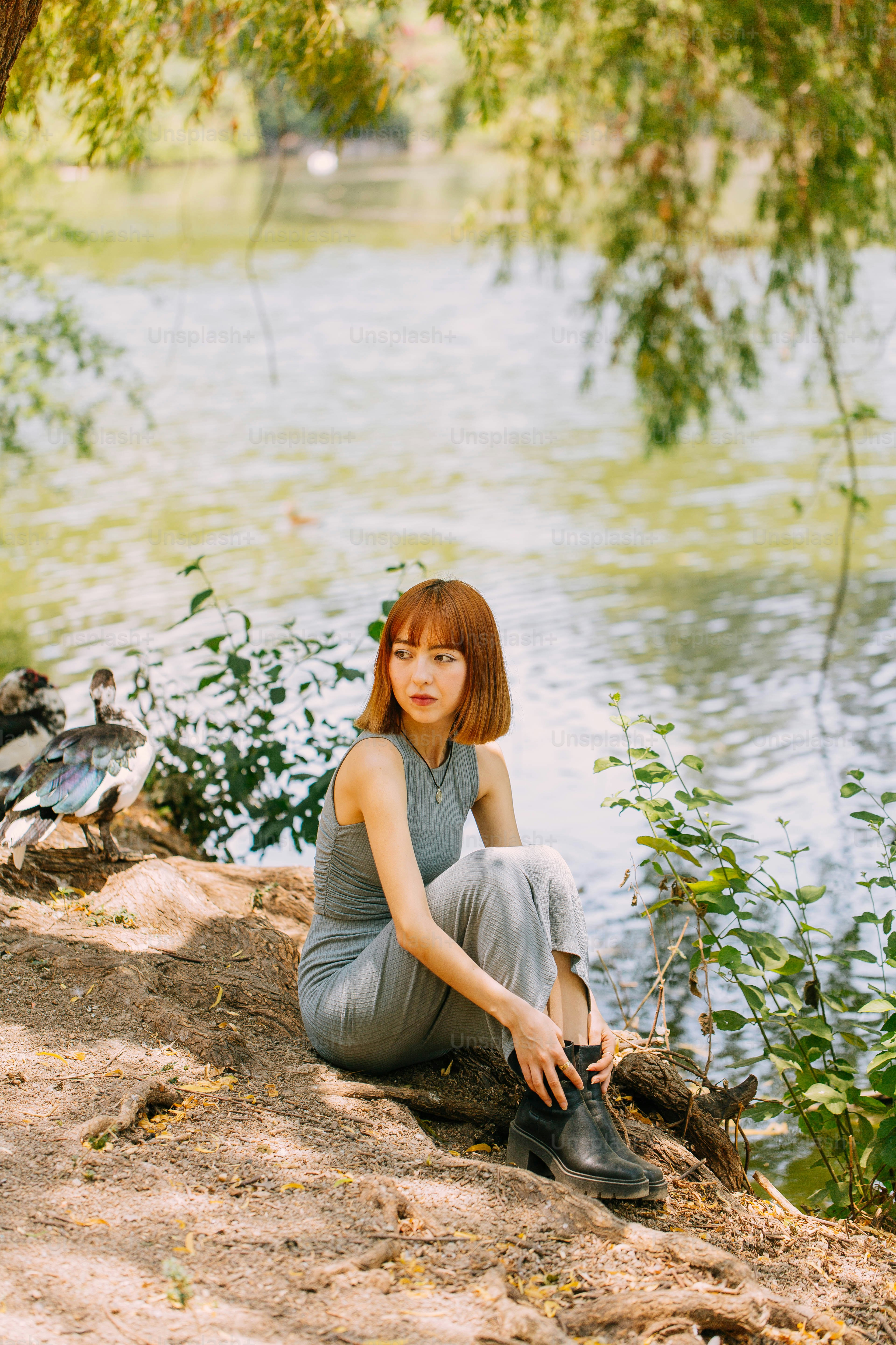 a woman sitting on a rock next to a body of water