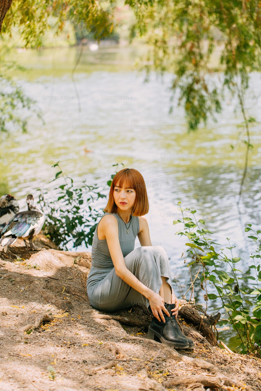 a woman sitting on a rock next to a body of water