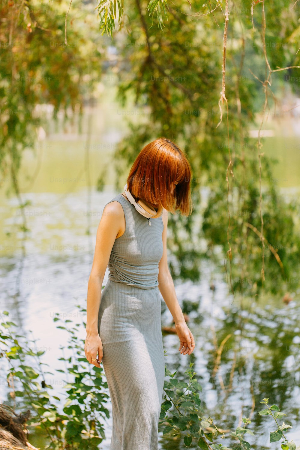 a woman with red hair is standing near a body of water