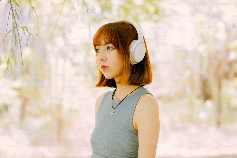 a woman wearing headphones standing under a tree
