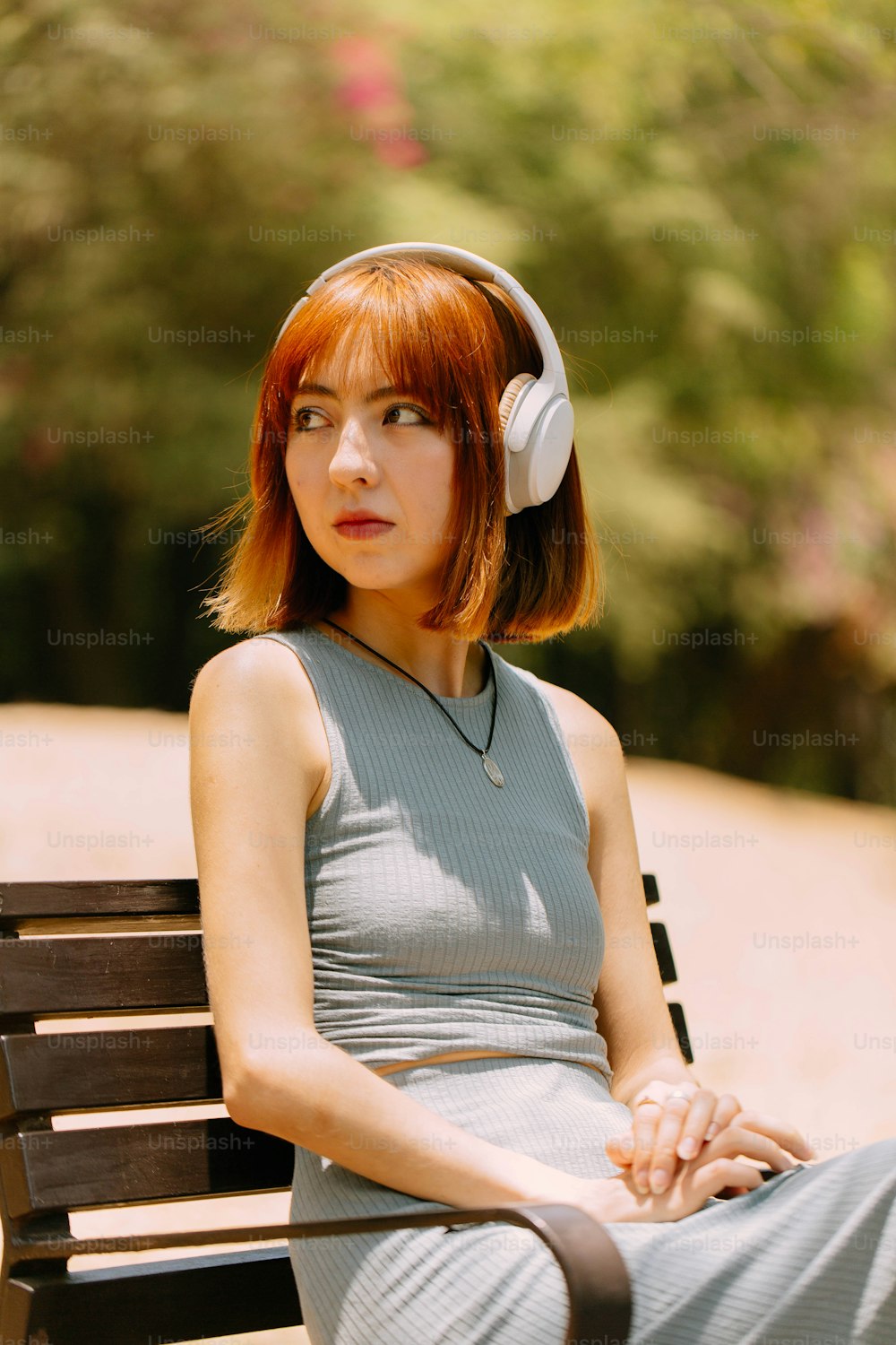 uma mulher com fones de ouvido sentada em um banco
