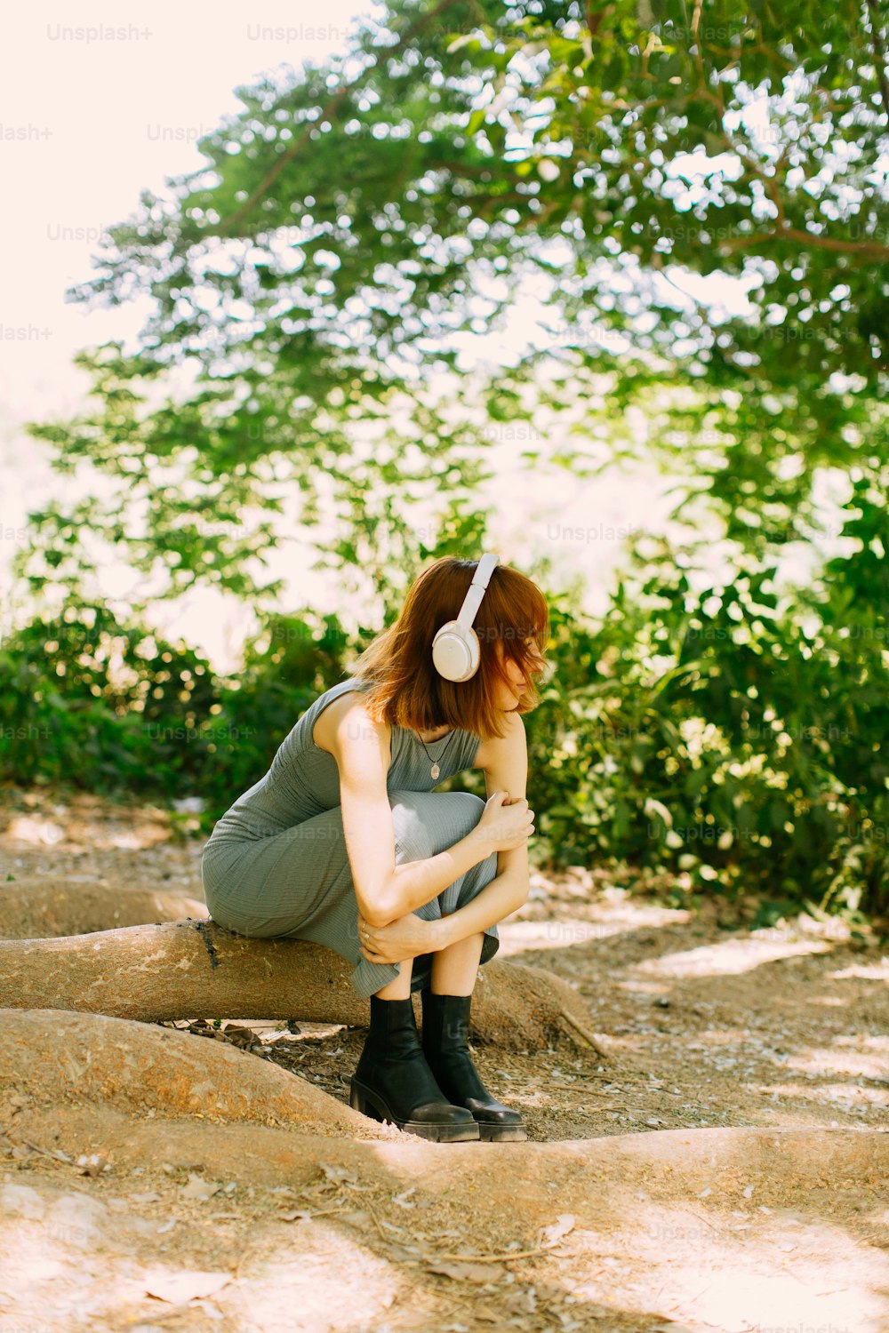 a woman sitting on a rock with headphones on