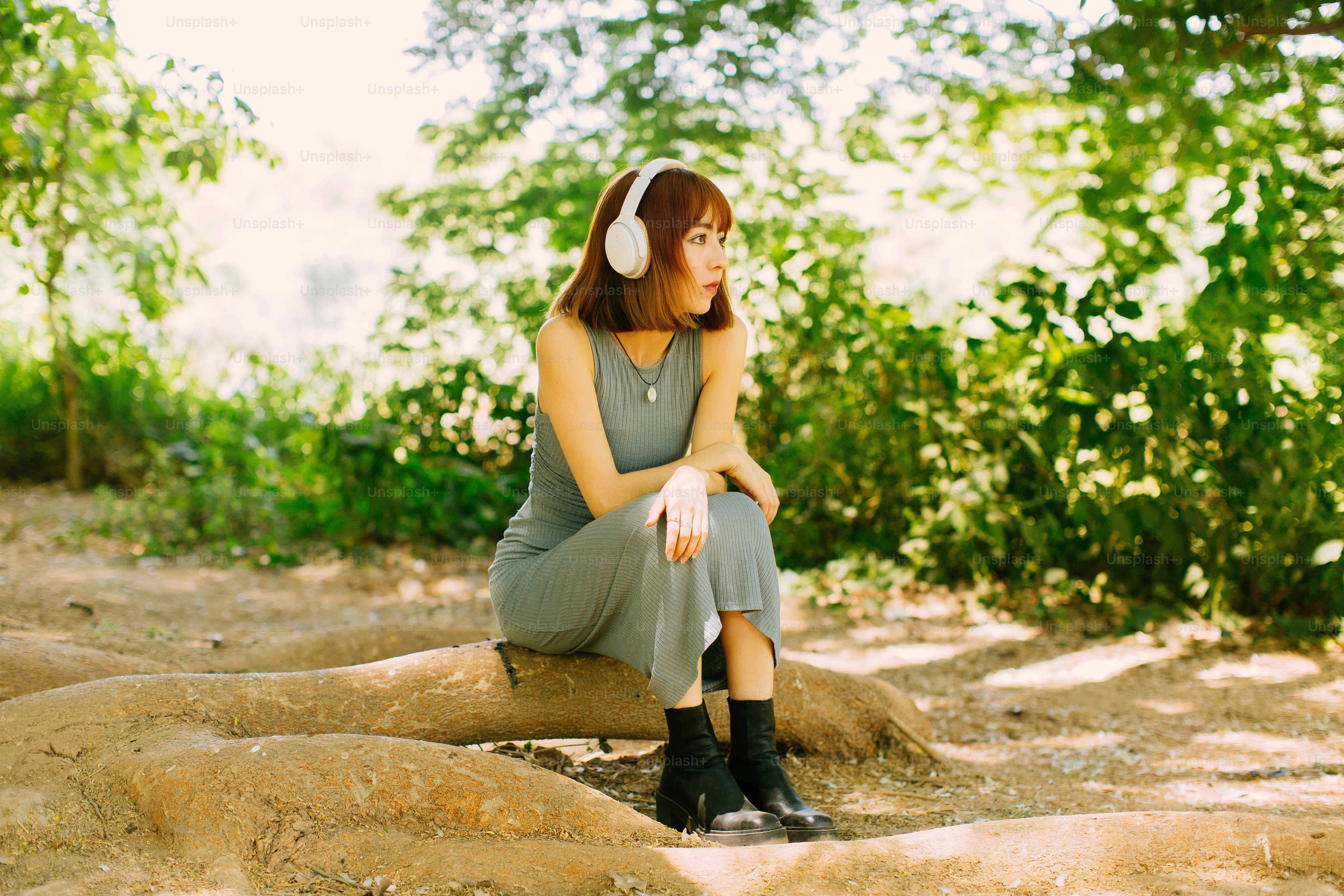 a woman sitting on a rock with headphones on