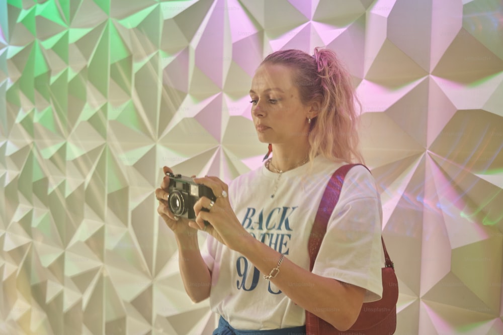 a woman holding a camera in front of a wall