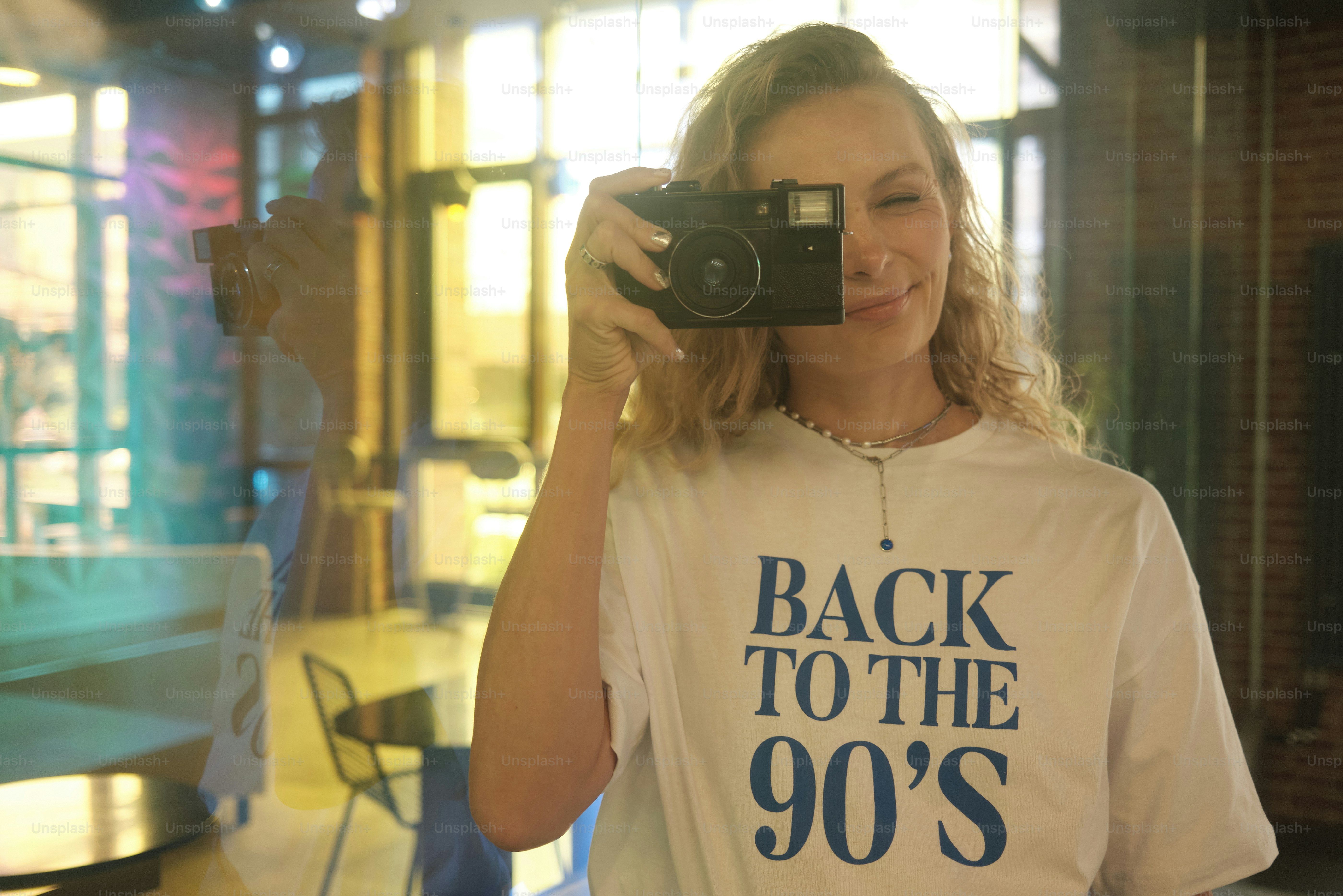 girl in a cafe taking pictures with a film camera