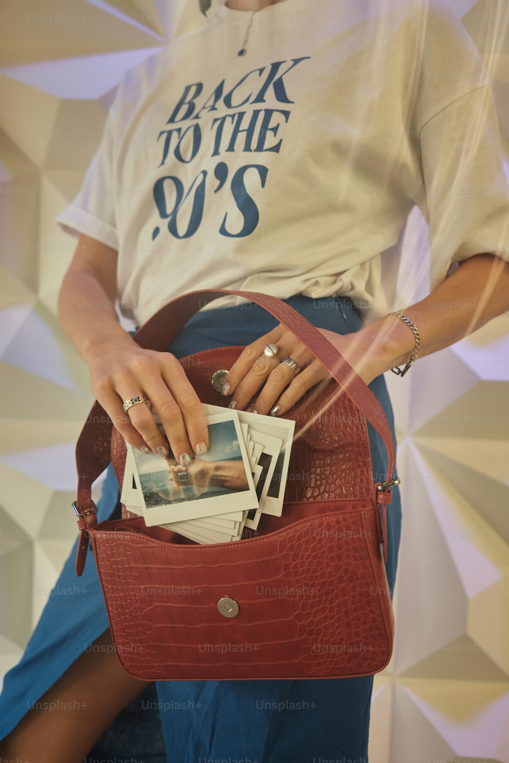 a woman holding a red purse with photos in it