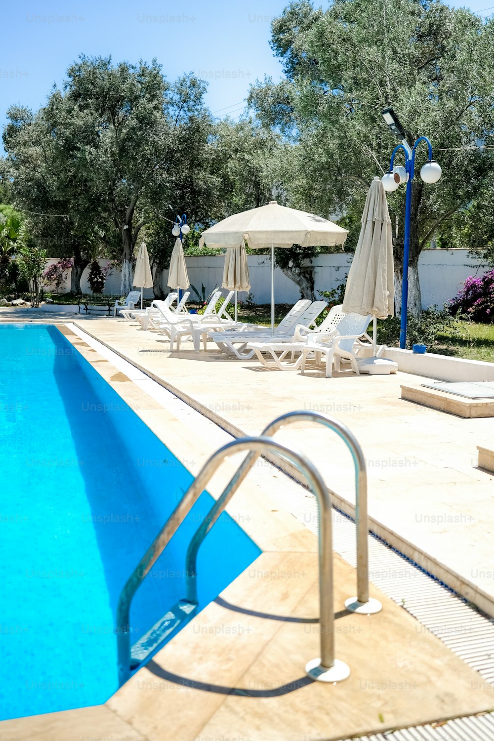 an empty swimming pool with chairs and umbrellas
