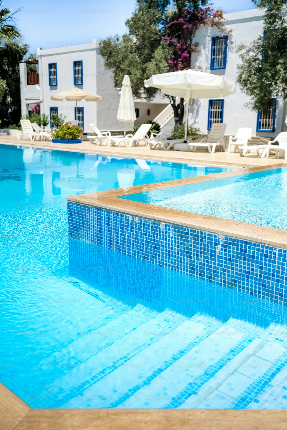 a large swimming pool with chairs and umbrellas