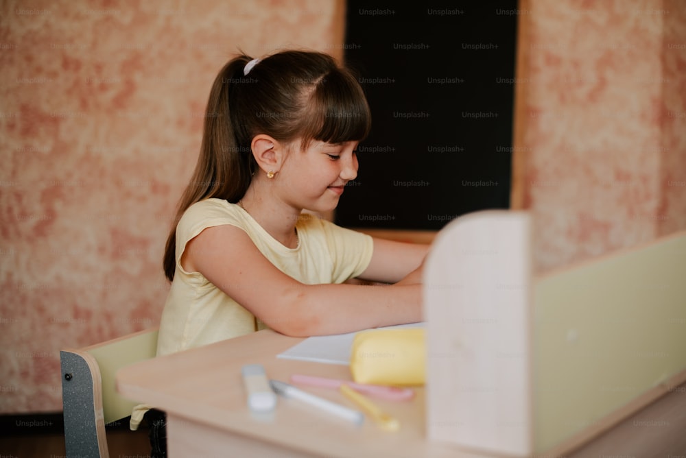 uma menina sentada em uma mesa com um laptop