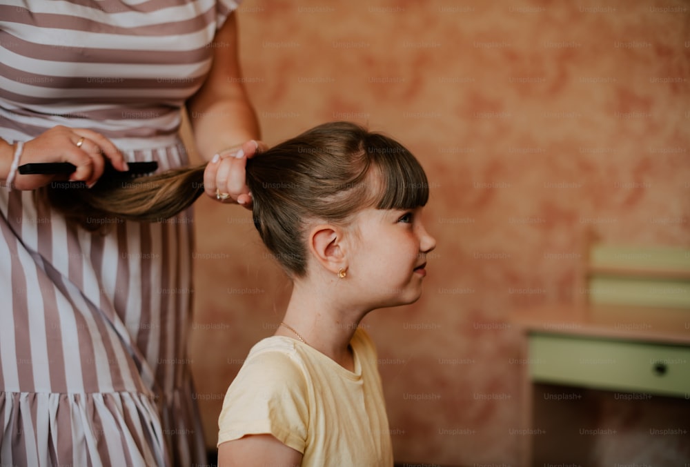 a little girl getting her hair cut by a woman