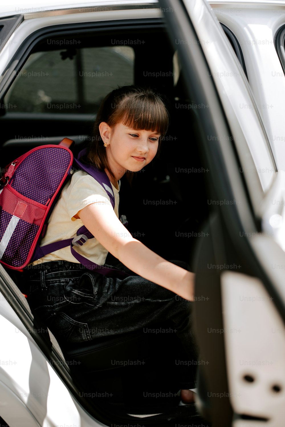 a young girl sitting in the passenger seat of a car
