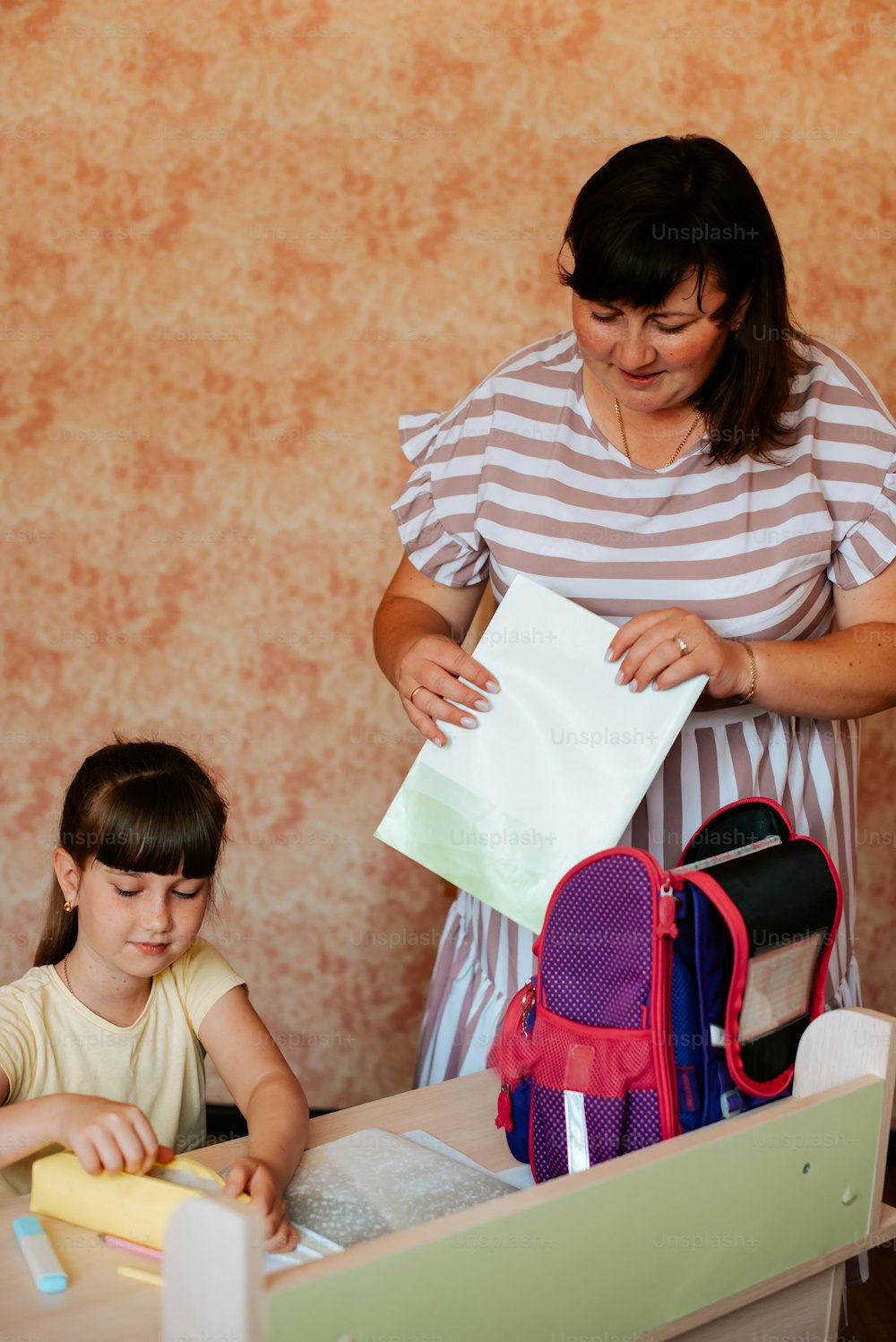 a woman standing next to a little girl in front of a laptop computer