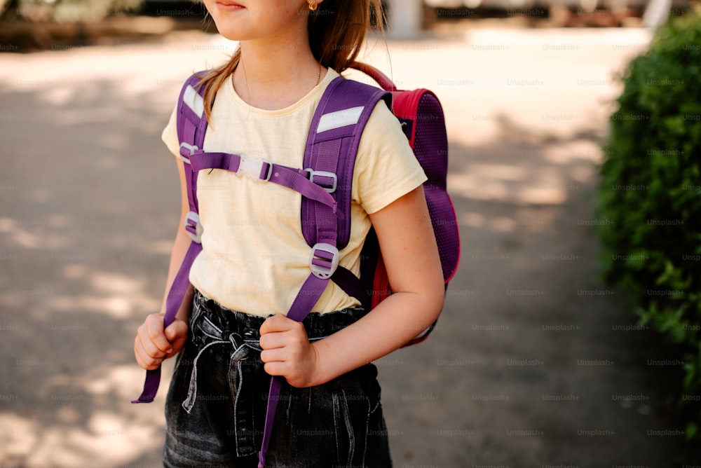 ein junges Mädchen mit einem lila Rucksack auf dem Rücken