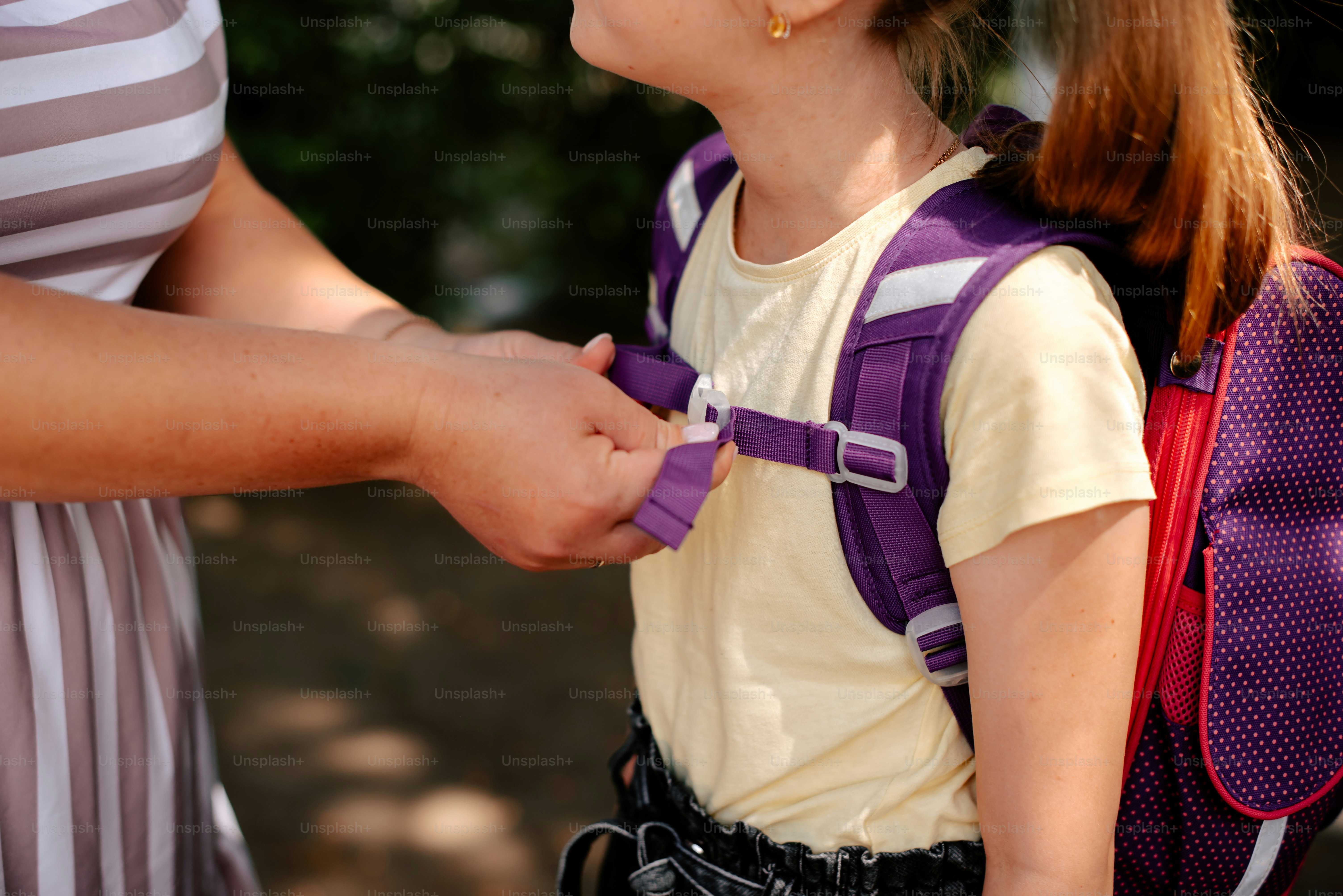 Student adjusting backpack fit before walking across campus with both shoulder straps properly positioned.