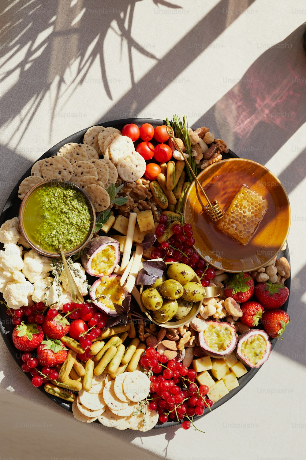 a platter of cheese, crackers, fruit, and dip