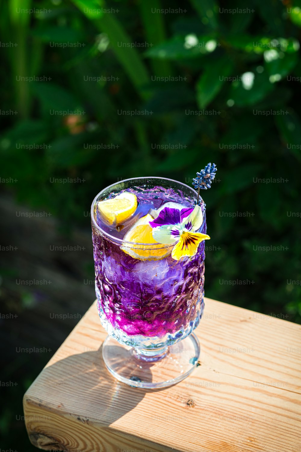 a purple drink with lemons and blueberries in a glass
