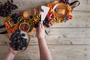 a person holding a plate of food in front of a platter of fruit and