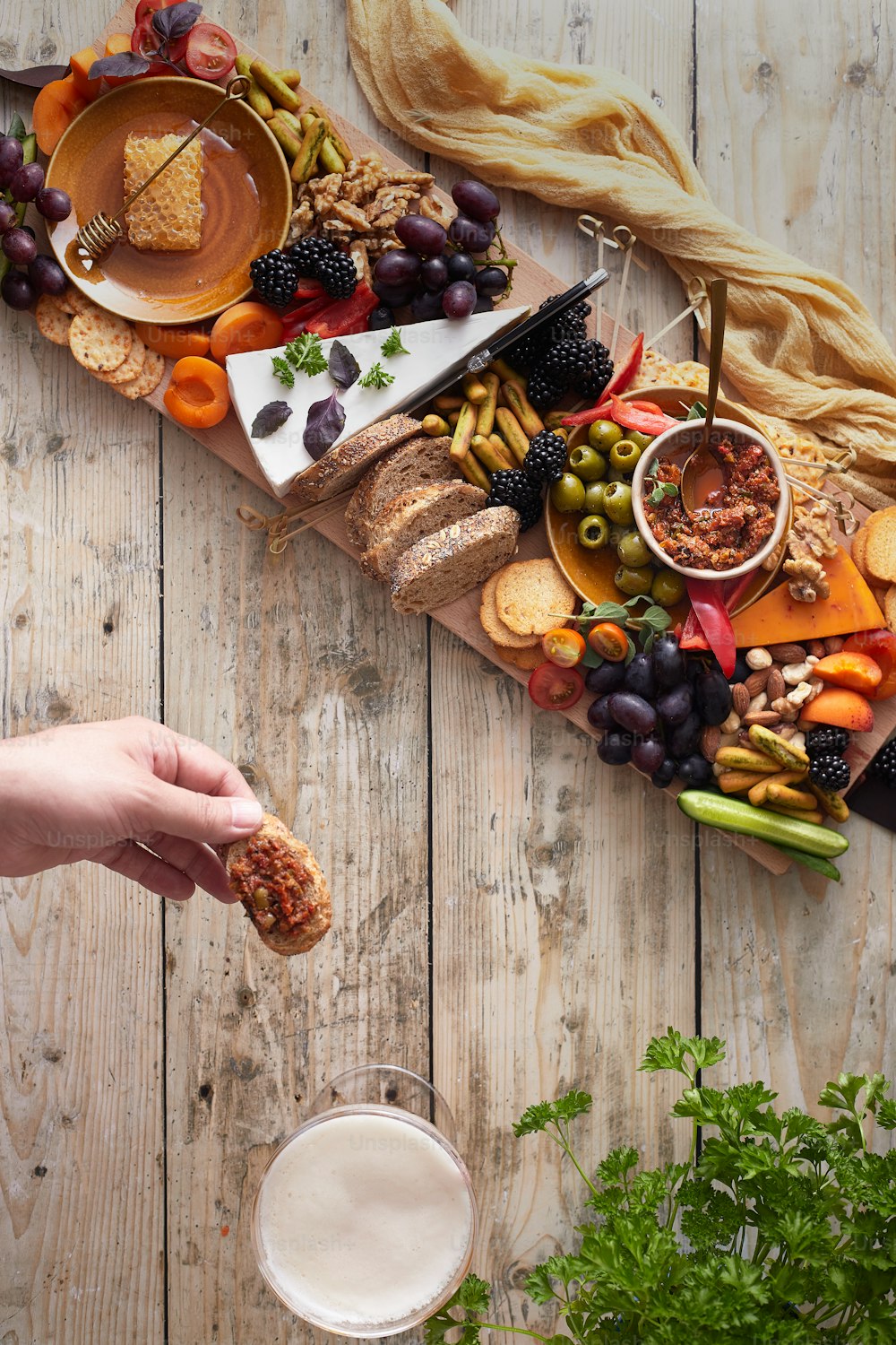 a person holding a piece of bread in front of a platter of food