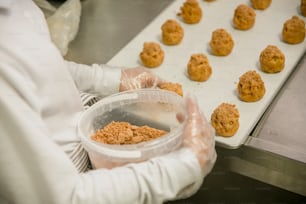a person in white gloves holding a container of food