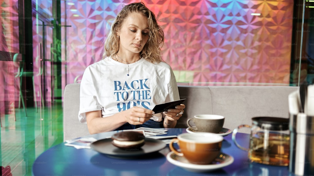 a woman sitting at a table looking at a tablet