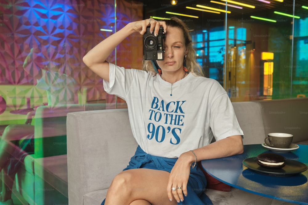 a woman sitting on a couch taking a picture with a camera