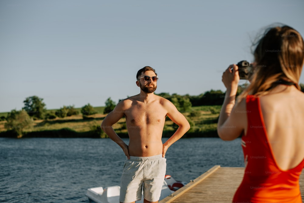 a man taking a picture of a woman on a dock