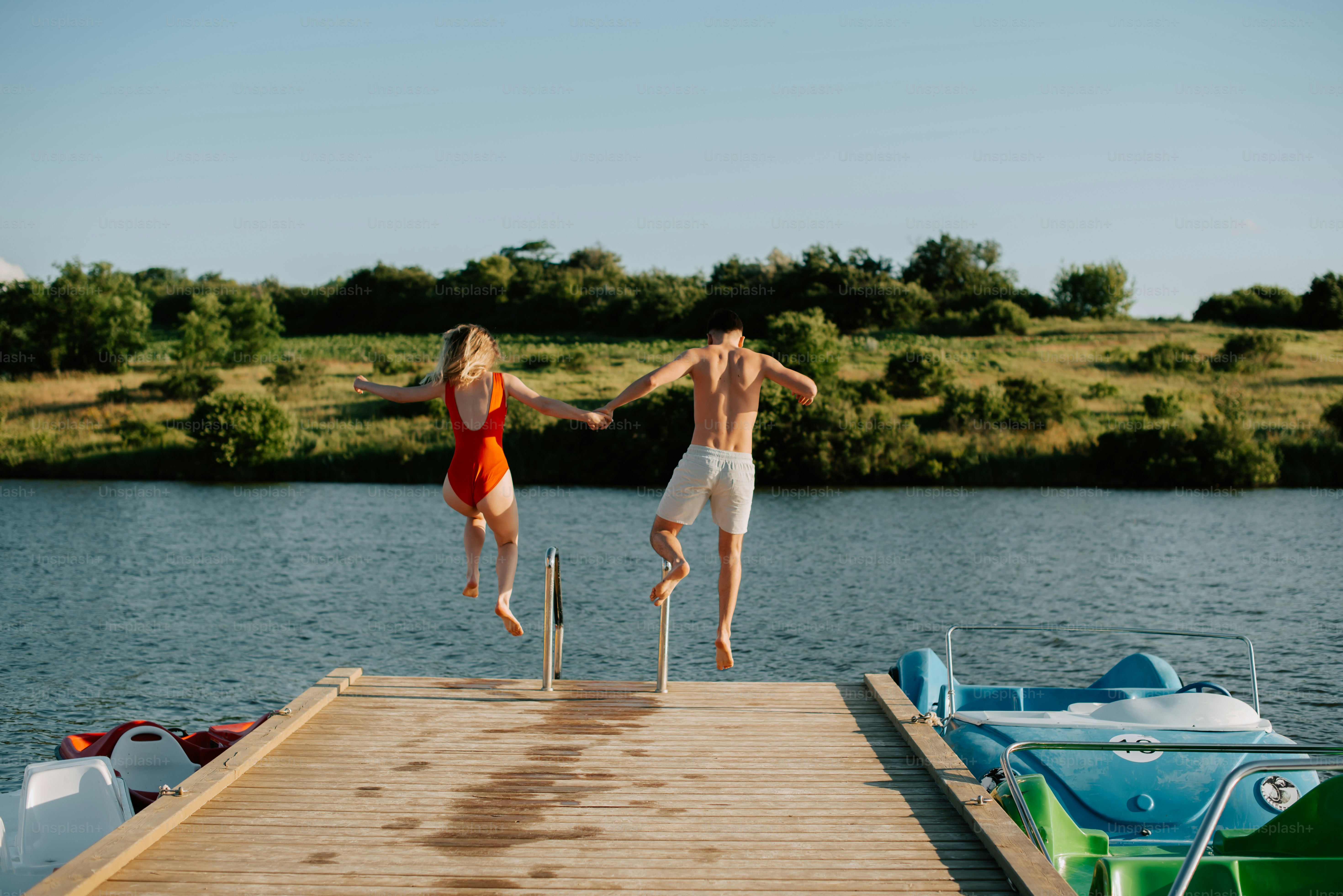 two people jumping off a dock into the water