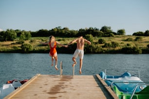 two people jumping off a dock into the water