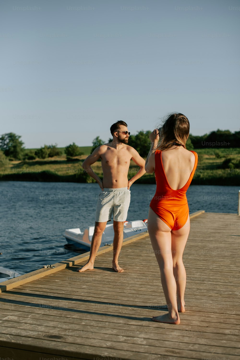 a man and woman standing on a dock next to a body of water