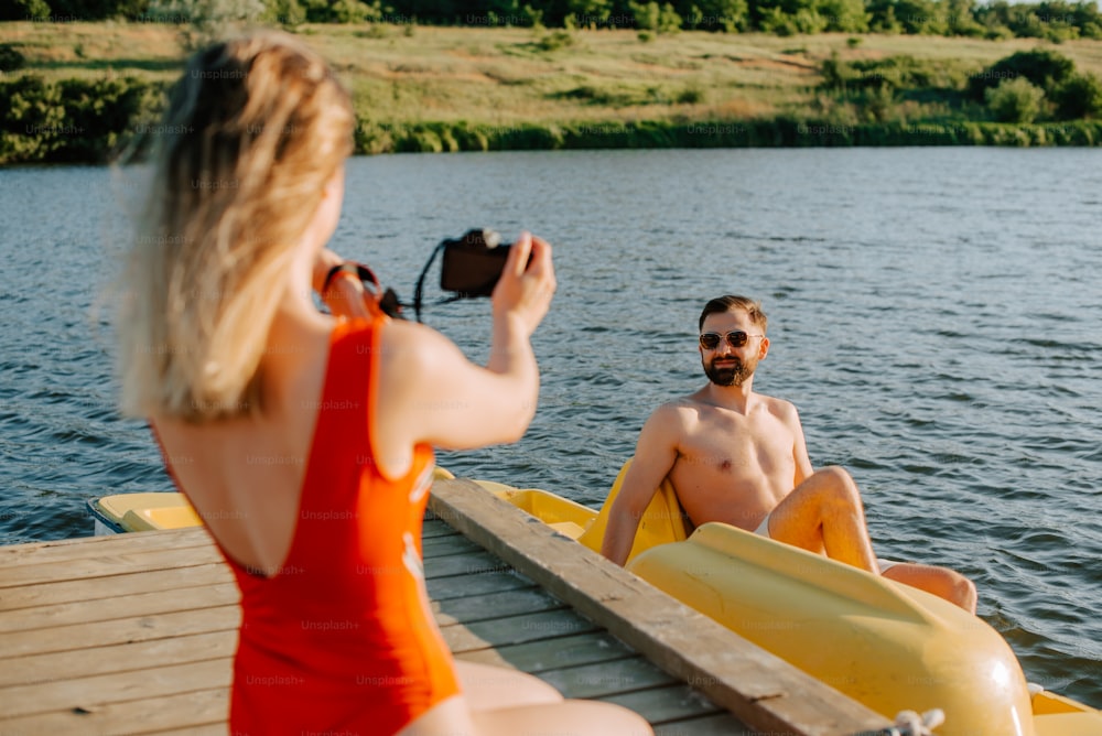 um homem tirando uma foto de uma mulher em um barco