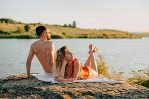 Un homme et une femme assis sur un rocher au bord de l’eau