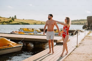 a man and a woman standing on a dock next to a body of water