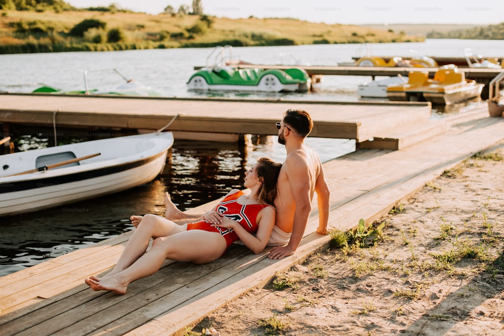 a man and a woman sitting on a dock next to a boat