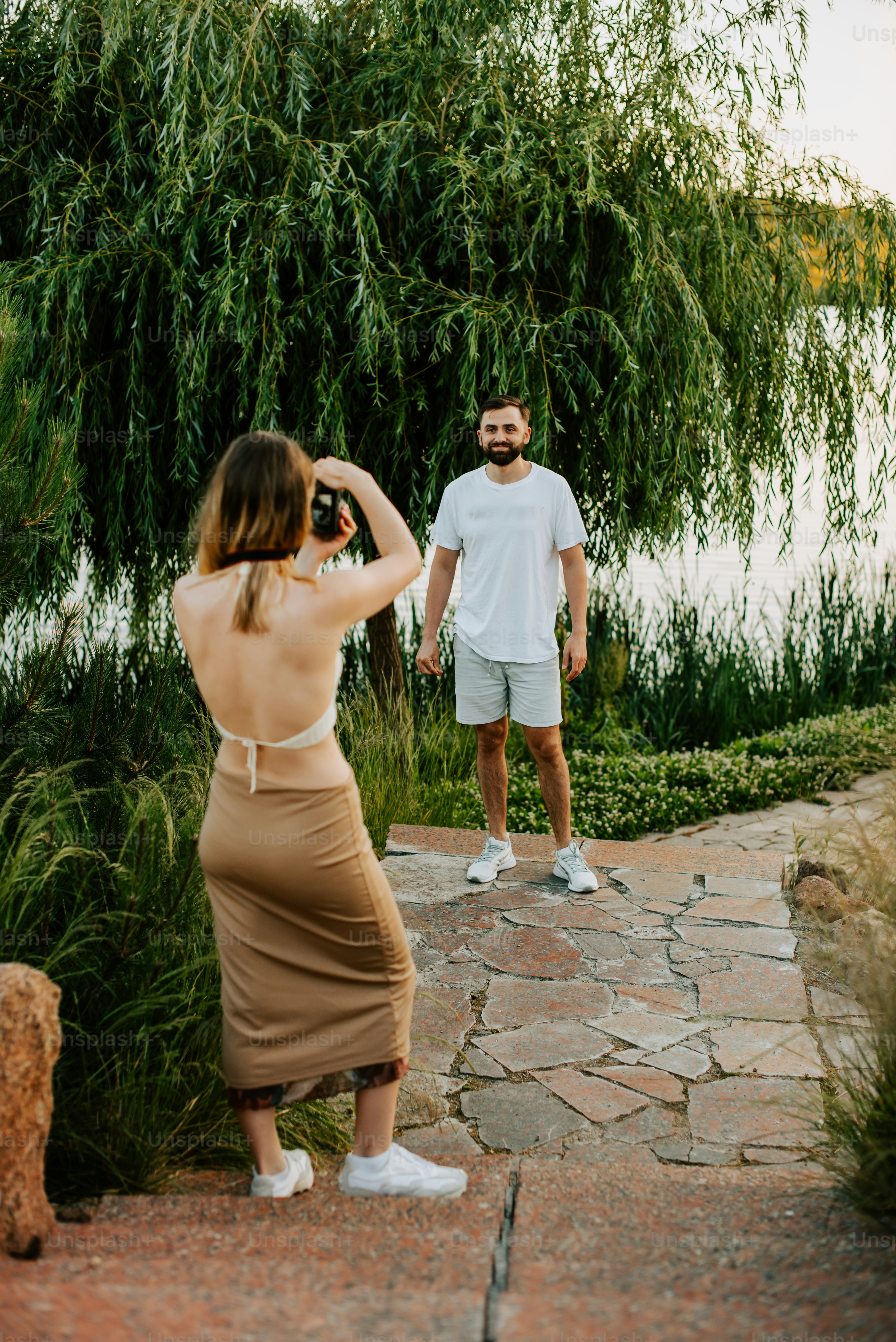 Woman photographing man by a lake